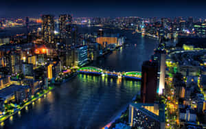 夜晚的城市，燈火通明的建築物和水面上發光的橋樑。 — 未來城市 壁紙