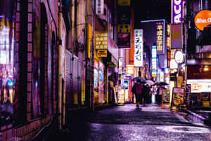 行人撐傘走過東京夜晚雨中的霓虹小巷。 — 日本 壁紙