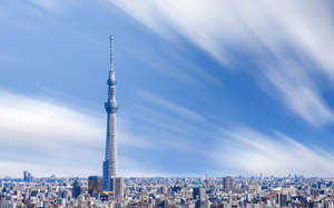 東京晴空塔高聳於城市上空，映襯著帶有條紋雲朵的明亮藍天。 — 日本 壁紙