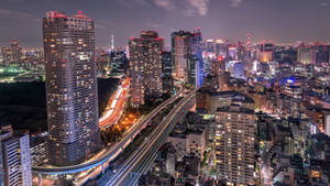 夜晚的東京城市景觀，燈火通明的建築物和交通光跡。