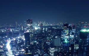 密集城市天際線的夜景，建築物和街道閃閃發光。 — 城市 壁紙