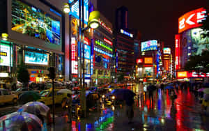 夜晚的東京街道，霓虹燈在濕漉漉的人行道上反射，人們撐著雨傘。 — 日本 壁紙