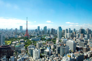 東京城市景觀，東京塔和現代摩天大樓在明亮的藍天下。