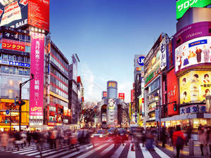 霓虹燈照亮嘅東京街道，黃昏時模糊嘅行人正在過馬路。