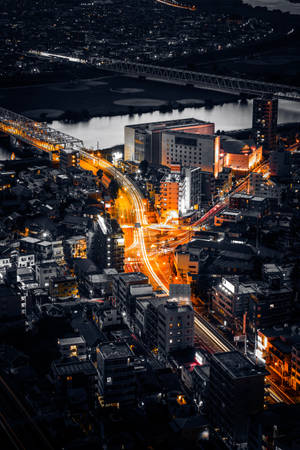 夜間城市景觀，帶有發光的橙色交通軌跡和燈火通明的建築物。