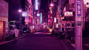 夜晚霓虹燈照亮東京小巷，有發光招牌和停泊的汽車。 — 日本 壁紙