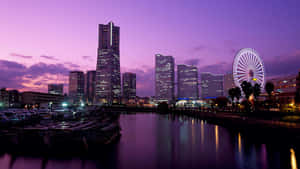暮色中的城市天際線，摩天輪和摩天大樓倒映在水中。 — 日本 壁紙