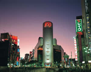 黃昏時分的東京天際線，明亮的霓虹燈和突出的圓柱形建築。 — 日本 壁紙