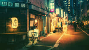 夜晚溫暖照亮的日本街道，有木製商店和一輛停著的自行車。 — 城市 壁紙