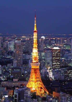 東京塔在夜晚亮起，背景是城市燈光。 — 日本 壁紙