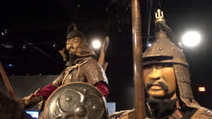 兩個穿著盔甲的戰士模特兒在燈光昏暗的博物館展覽中展示。 — 曼達洛人 GIF 壁紙
