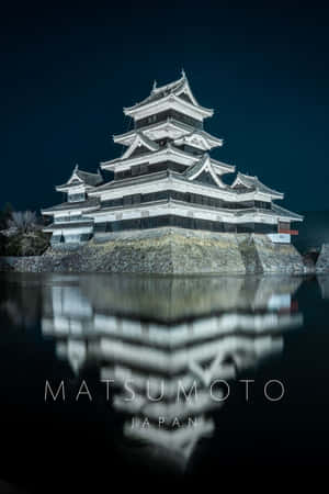 松本城在夜晚發光，水面倒影完美。 — 日本 壁紙