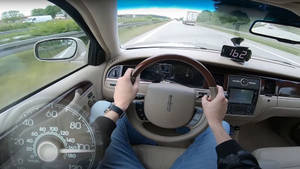 一個人在陽光明媚的高速公路上駕駛豪華車，雙手放在方向盤上。 — 酷車 壁紙