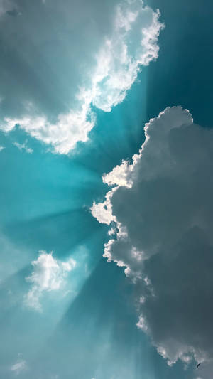 陽光穿過蓬鬆的白雲，在明亮的藍天中閃耀。