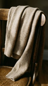 米色針織毛衣披在木椅上，光線溫暖。