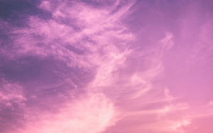 粉紅色和紫色的天空，帶有在日落時發光的縷縷雲彩 — 唯美雲朵動態 壁紙
