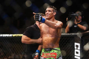 UFC拳手在八角籠內慶祝勝利，裁判和人群在後面。