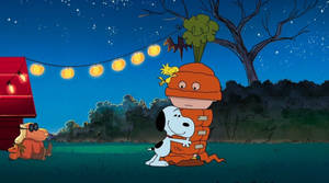 Snoopy 和 Woodstock 在夜晚的燈串下穿著萬聖節服裝。
