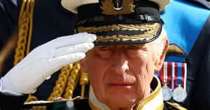 年長海軍軍官穿著正式制服敬禮，帶有勳章和金色飾邊。 — 政治 壁紙