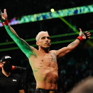 UFC拳手在八角籠中高舉雙臂慶祝勝利。