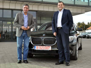 兩名男子在汽車經銷商處與黑色BMW SUV合影。