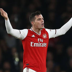 身穿紅色阿仙奴球衣的足球運動員在夜晚高舉雙臂慶祝。 — 足球 壁紙