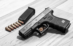黑色手槍連彈匣及子彈在木質表面上。 — Glock GIF 壁紙