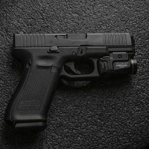 黑色 Glock 手槍配備激光瞄準器，置於紋理背景上