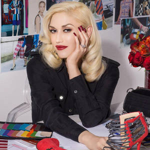 Gwen Stefani 在時尚工作室中，周圍環繞著設計材料和紅色配飾。 — 卡通鞋 壁紙