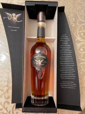 Gran Centenario Leyenda 龍舌蘭酒瓶放在黑色豪華盒子中，置於圖案布料上。