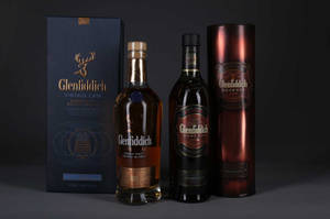 深色表面上的三瓶 Glenfiddich 威士忌和盒子。