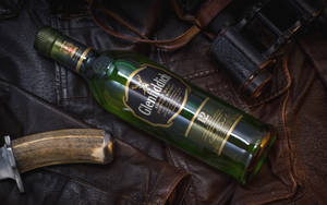 Glenfiddich 威士忌酒樽喺皮革上，附有刀同望遠鏡。