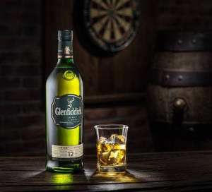 Glenfiddich 威士忌酒樽同有冰嘅酒杯放喺酒吧嘅木枱上。