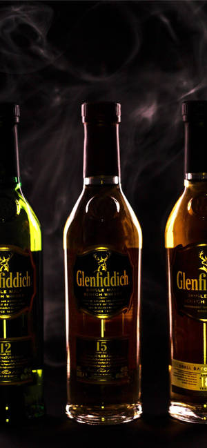 三瓶 Glenfiddich 威士忌在黑暗環境中帶有煙霧。