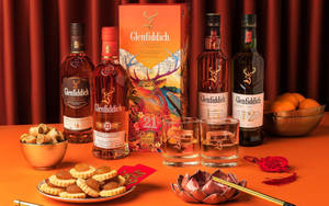 Glenfiddich 威士忌酒瓶和農曆新年美食在橙色桌子上。