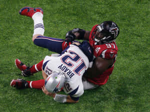 足球員在夜間比賽中被攔截在草地上。 — NFL 美式足球 GIF 壁紙