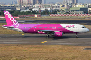 Peach Airlines飛機在跑道上，背景有城市天際線