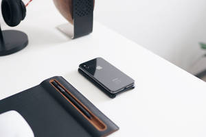 白色桌子上的黑色iPhone，配有耳機和揚聲器