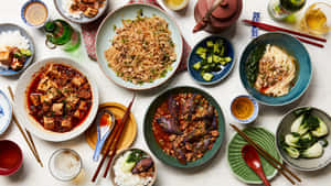 色彩繽紛的亞洲菜餚，包括麵條、豆腐和茄子，盛在陶瓷碗中，附有筷子和飲料。