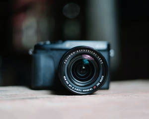 黑色 Fujifilm 相機配備 Fujinon 鏡頭，在木質表面上柔和對焦。