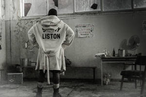 穿著 Sonny Liston 長袍的拳擊手站在破舊的訓練室中。 — 暗色 壁紙