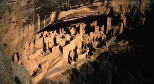 金色陽光下，砂岩中雕刻的古代懸崖住所遺址。