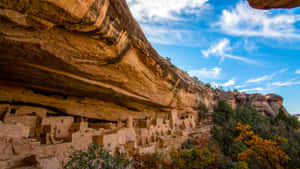 在藍天和秋樹下，建在砂岩懸崖上的古老懸崖住所。