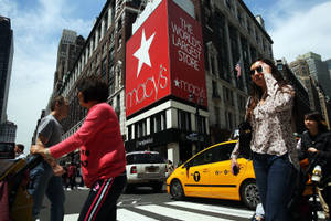 人們在黃色出租車和 Macy's 商店標誌的背景下穿過紐約繁忙的街道。