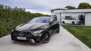 啞光黑色Mercedes-AMG GT停泊在現代玻璃車庫外，裡面有一輛白色AMG。