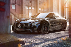 日落時分，黑色Mercedes-AMG GT停在工業城市環境的礫石上。