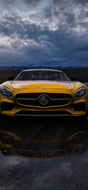 暴風雲下濕滑路面上的黃色 Mercedes-AMG GT 跑車。