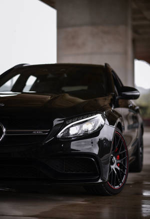 黑色 Mercedes-AMG 跑車帶有紅色點綴，停放在混凝土車庫中。