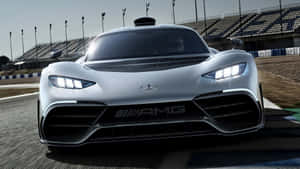 銀色 Mercedes-AMG 賽車在賽道上，車頭燈明亮，看台空無一人。
