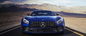 藍色 Mercedes-AMG GT 跑車在沙漠公路上，後面有山。